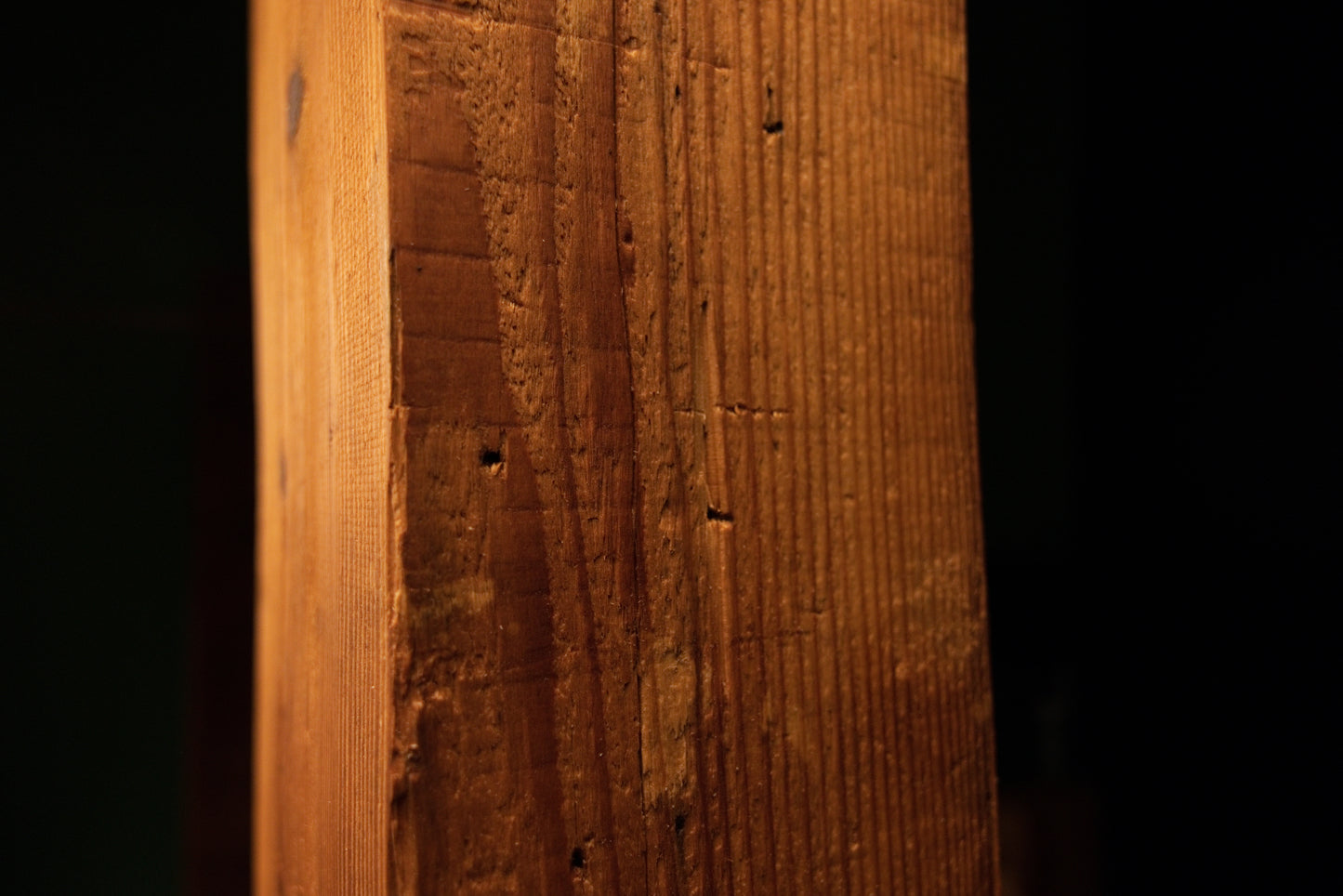 Detailed macro perspective showing vertical wood grain patterns and weathered surface details on the timber beam. 