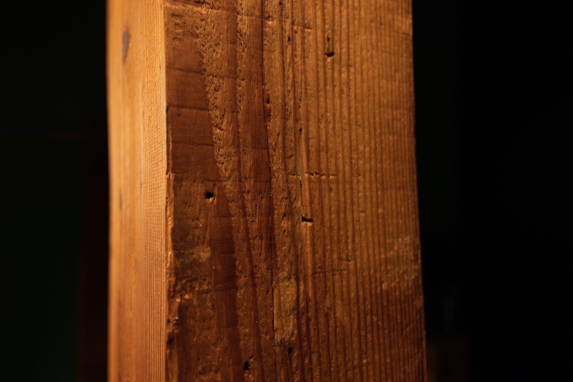 Detailed macro perspective showing vertical wood grain patterns and weathered surface details on the timber beam. 