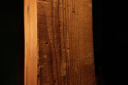 Detailed macro perspective showing vertical wood grain patterns and weathered surface details on the timber beam. 