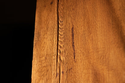 Close-up macro photograph of a narrow vertical surface split intersecting textured linear grain fibers on a timber block. 