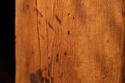 Macro view highlighting dark scratch marks and shallow surface gouges cutting across the linear grain of a climate-stable timber. 
