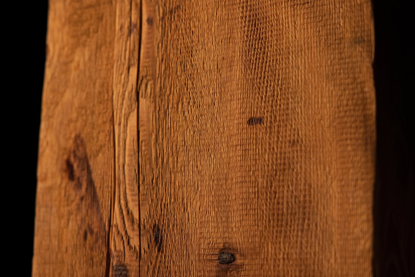Detailed macro photograph showcasing straight vertical grain patterns terminating near a dark organic knot on a beam edge. 