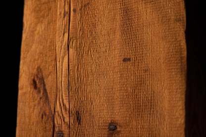 Detailed macro photograph showcasing straight vertical grain patterns terminating near a dark organic knot on a beam edge. 