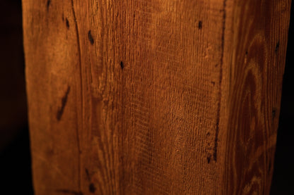 Close-up perspective of linear wood grain embedded with scattered pinholes and a subtle cathedral grain curve on the right. 