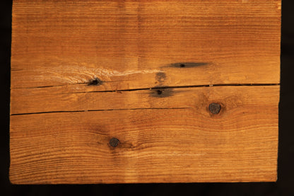 Flat surface view of a floor-heating compatible wooden plank displaying multiple dark organic knots and a horizontal check. 