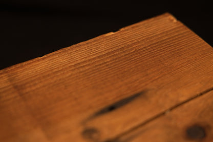 Close perspective view of the top edge and flat surface of a structural timber block showing fine linear grain lines. 