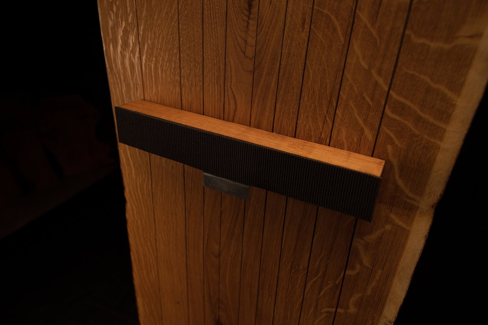 Close-up perspective of the middle dark horizontal mounting crossbar securely attached across vertical oak slats on the frame.