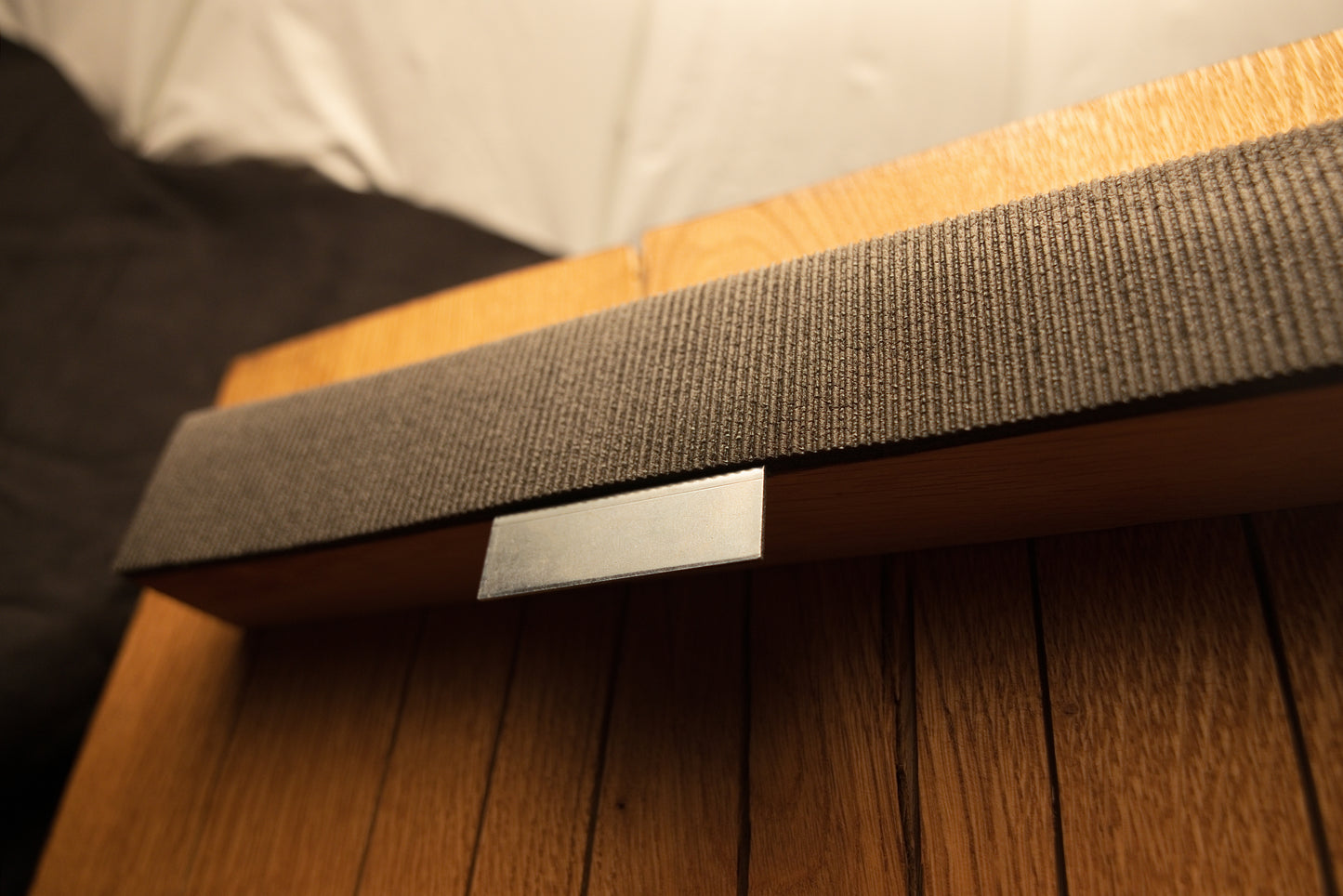 Angled macro perspective of the upper horizontal support bar featuring textured dark wrapping and an embedded metallic hardware plate.