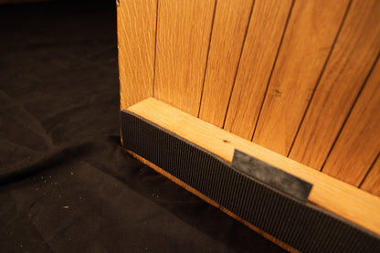 Close-up view of the lower horizontal mounting bracket securely fastened across the bottom edge of the vertical oak panel slats.