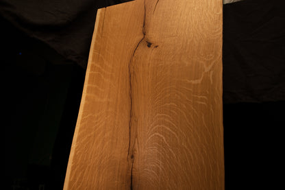Close-up macro of the upper section on the solid oak architectural panel showing the curved path of a stabilized natural fissure.
