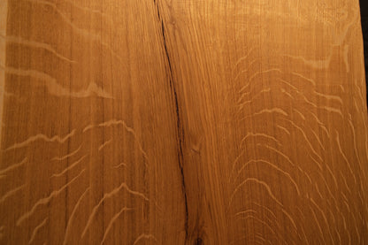 Detailed macro focus on the intersection between fine vertical wood grain and sweeping medullary ray reflections on the oak slab.