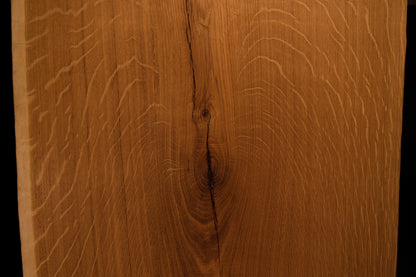 Close-up macro showing a natural wood knot splitting into a delicate fissure across the highly figured solid oak wooden panel face.
