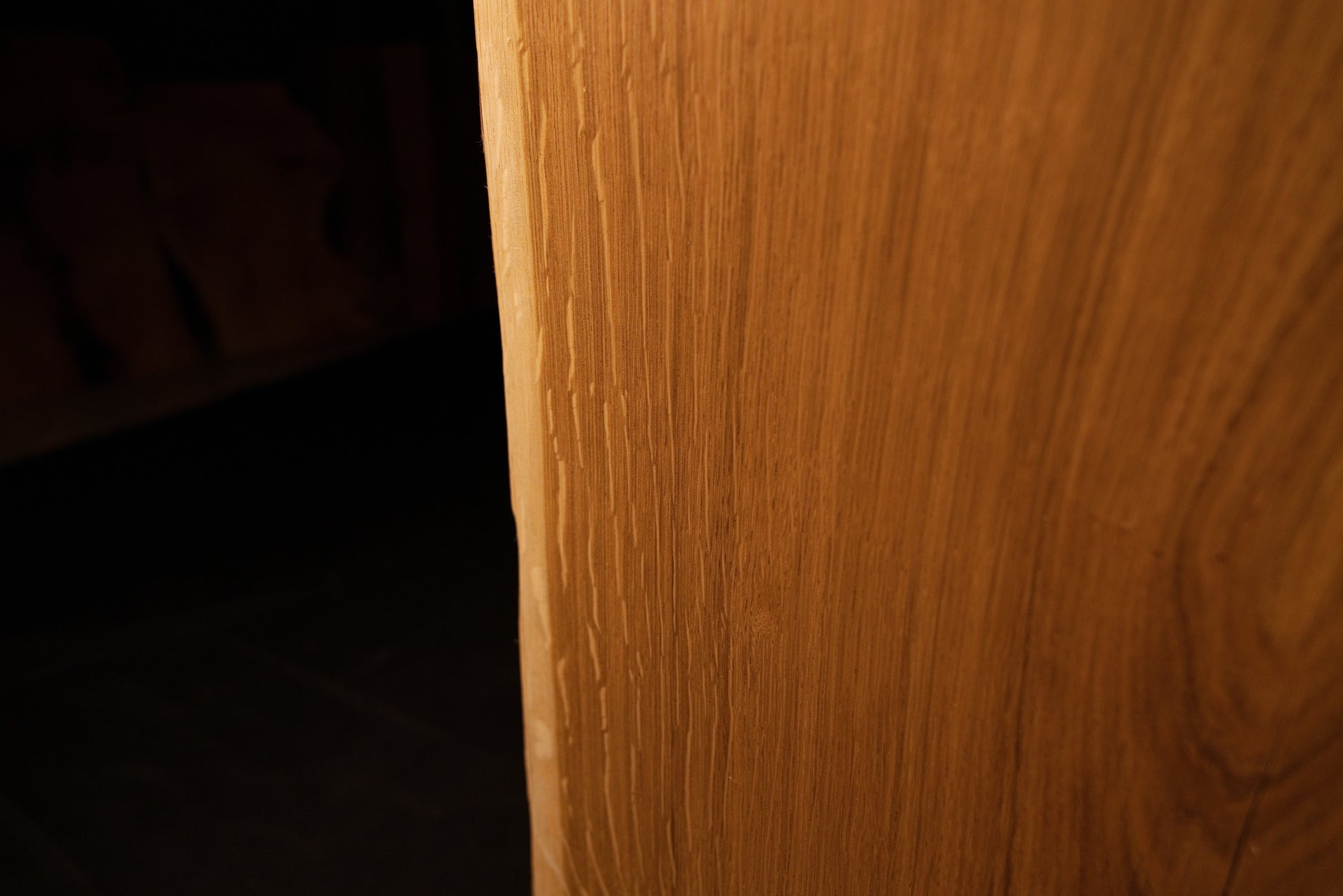 Macro perspective highlighting dense vertical wood fibers and rich golden tones on the face of the custom oak slab.