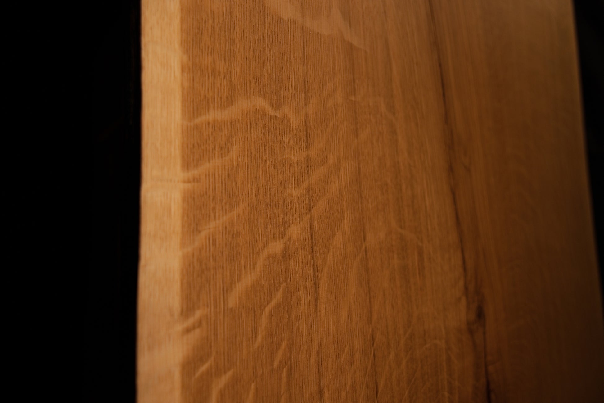 Extreme macro photograph focusing on the subtle natural grain variations and warm amber hues of the polished oak panel.