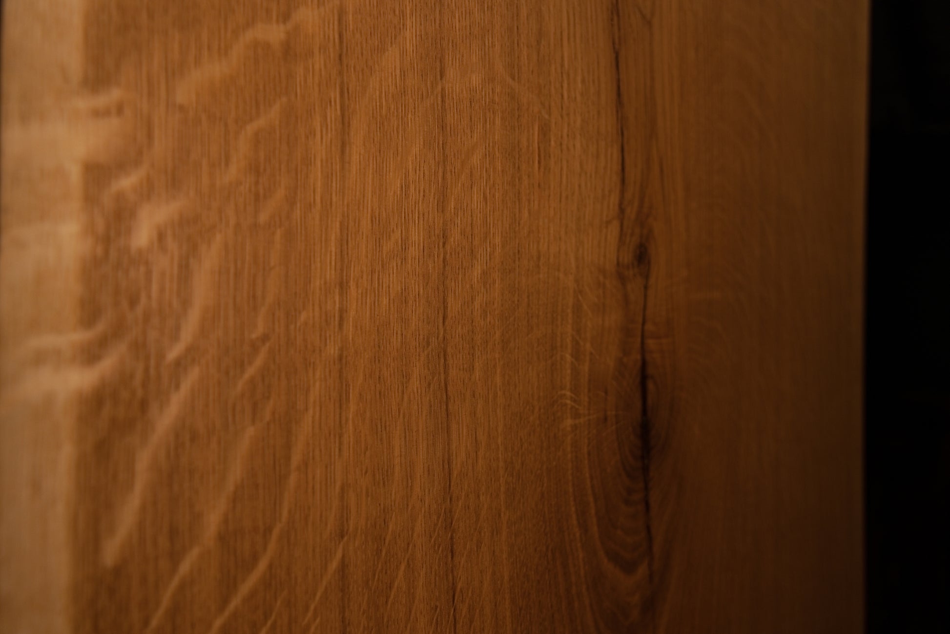 Macro close-up of vertical wood fibers and subtle grain variations along the polished outer edge of the solid custom oak board.