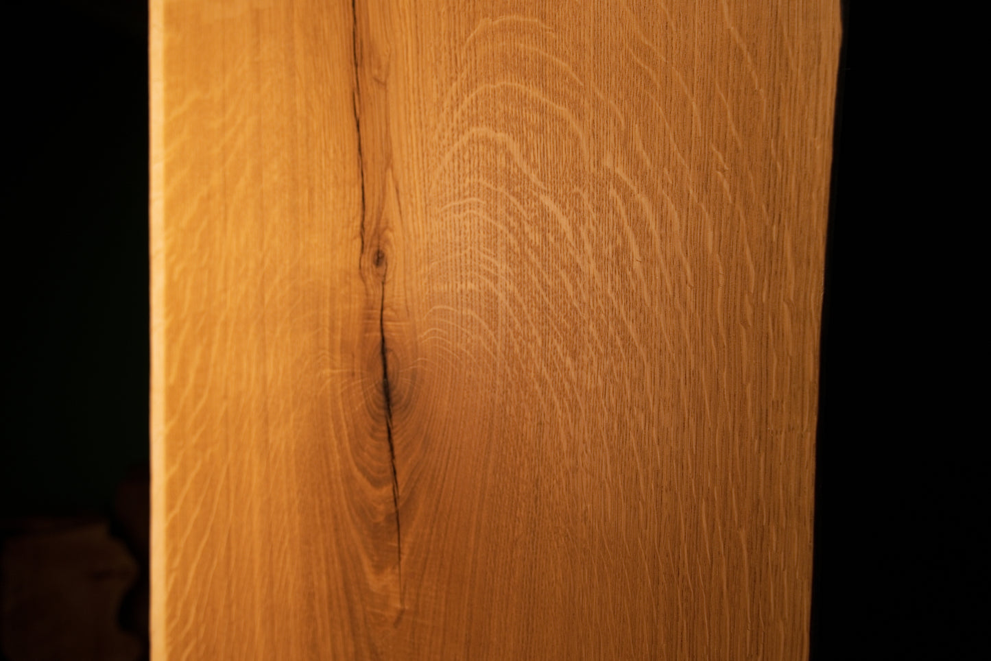 Straight vertical macro perspective of a tight natural fissure running through the highly figured grain of the custom oak board.