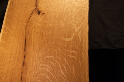 Close-up view of shimmering chatoyant medullary rays shifting across the warm golden surface of the custom architectural oak panel.