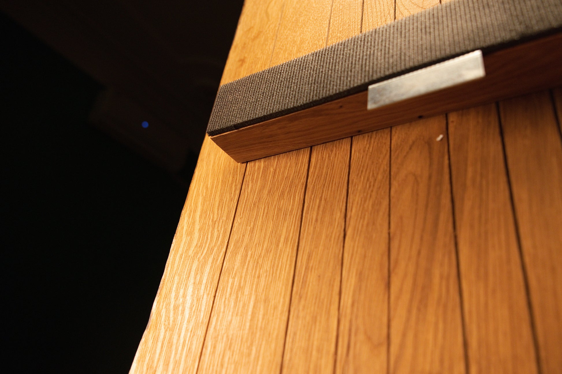 Close-up perspective of the top mounting crossbar securely attached across the vertical wooden slats of the custom oak panel. For mirror sides.