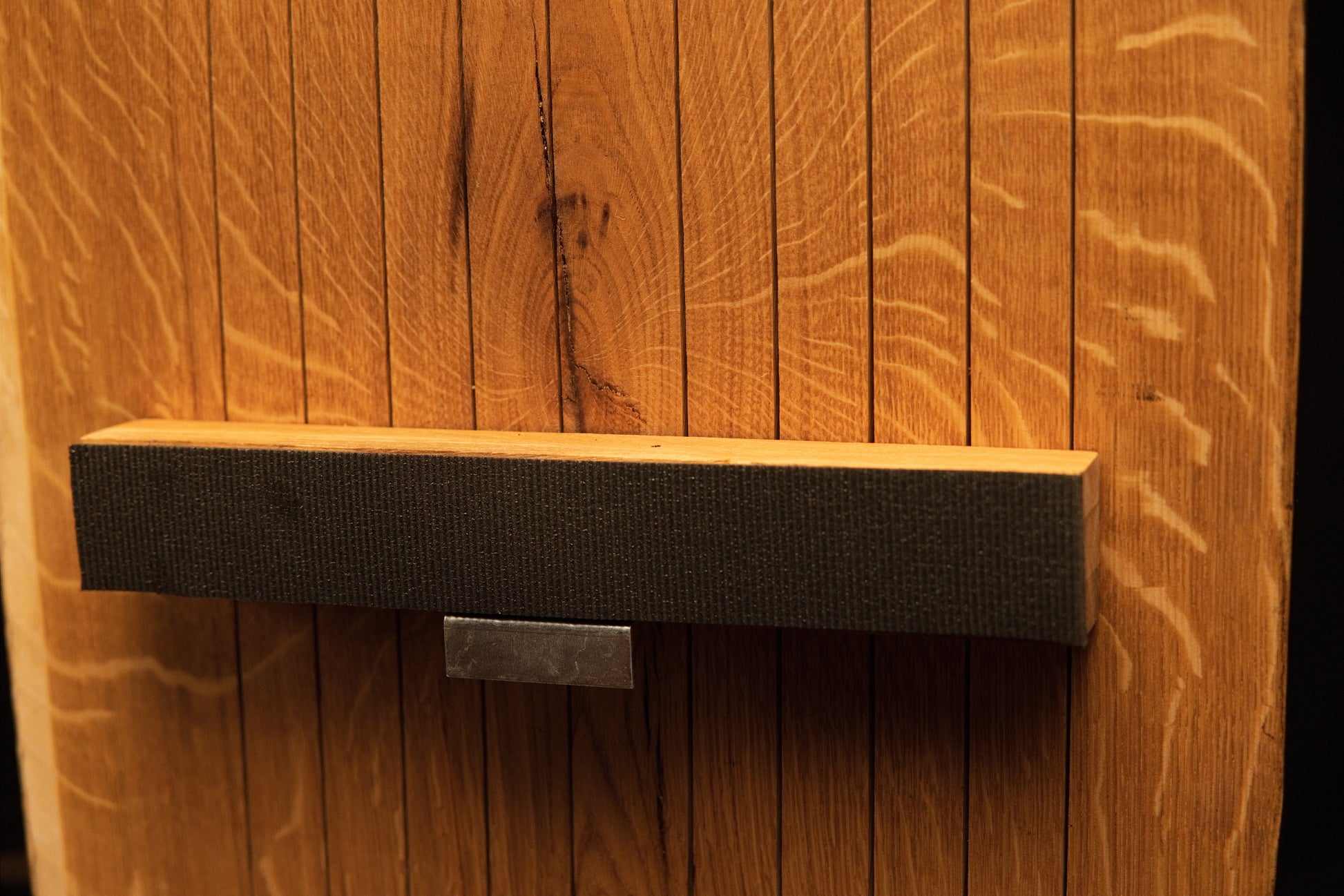 Close perspective of the middle dark horizontal mounting crossbar securely attached across vertical oak slats on the frame. 
