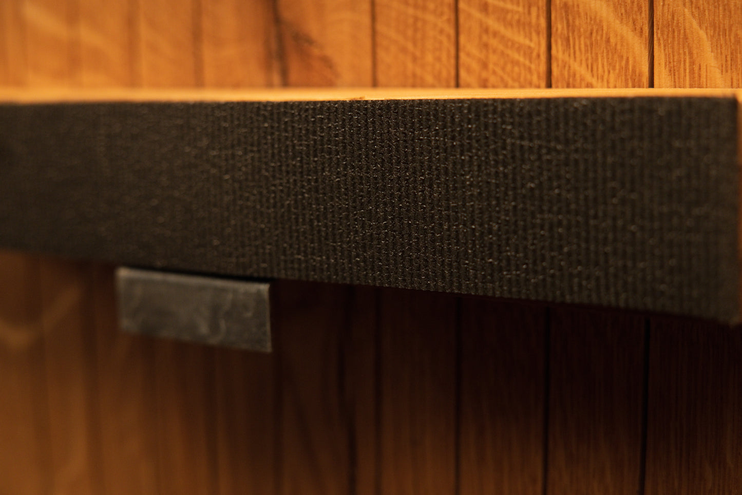Detailed view of the central support bar wrapped in textured fabric and secured with a polished metal hardware clip. 