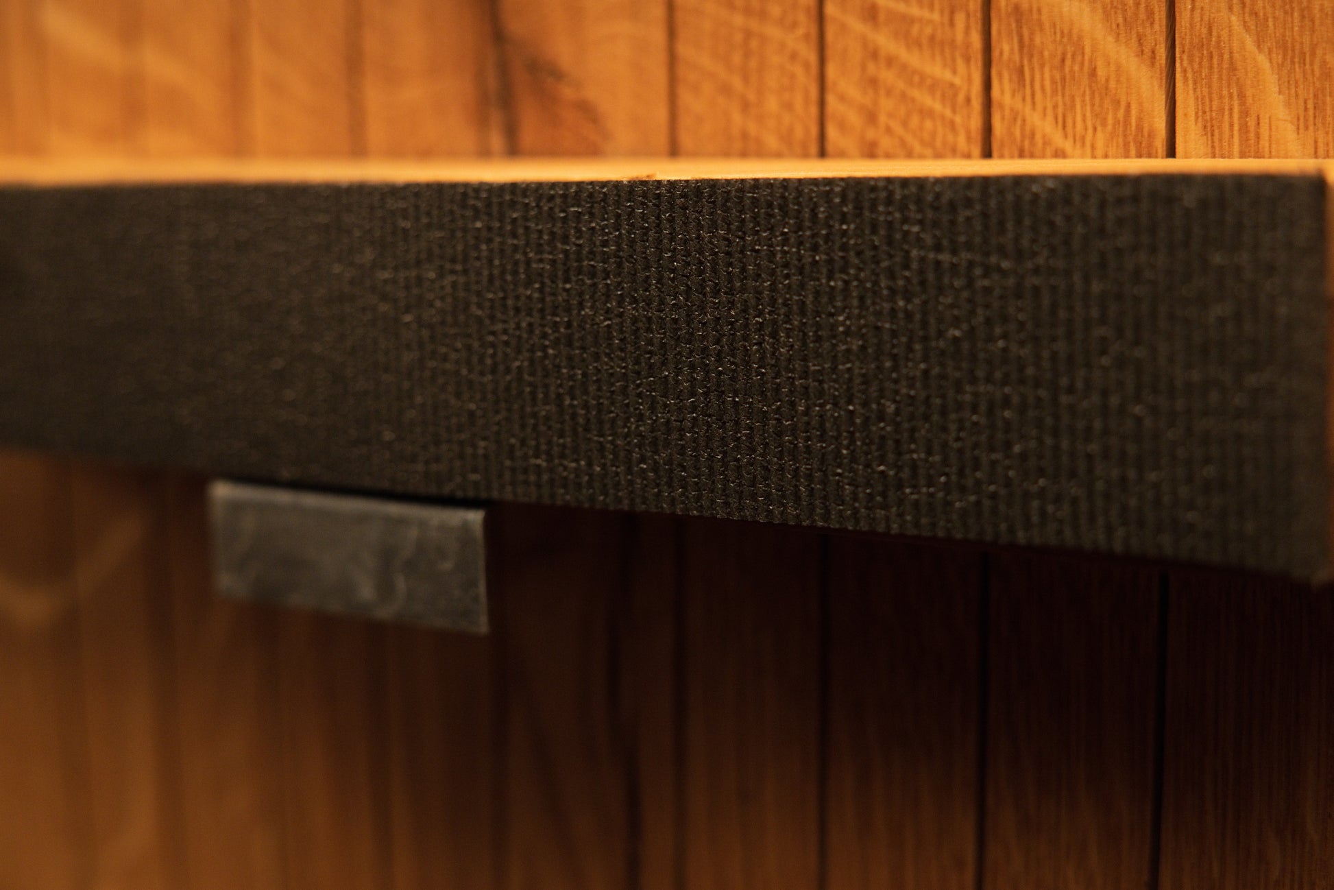 Detailed view of the central support bar wrapped in textured fabric and secured with a polished metal hardware clip. 
