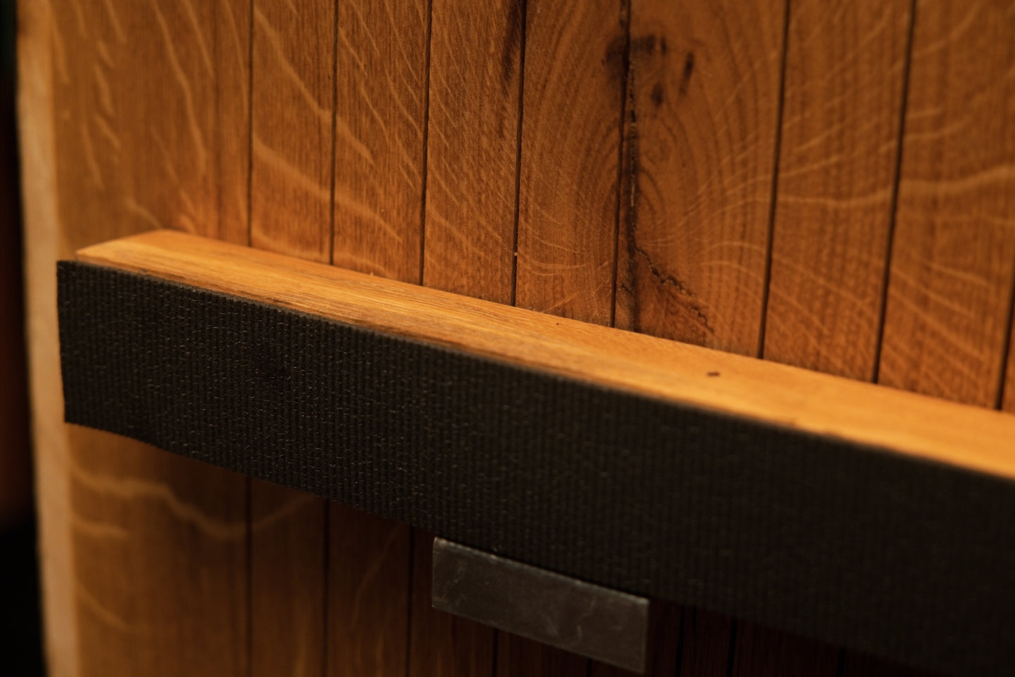Angled macro perspective of the upper horizontal support bar featuring textured dark wrapping and an embedded metallic plate. 