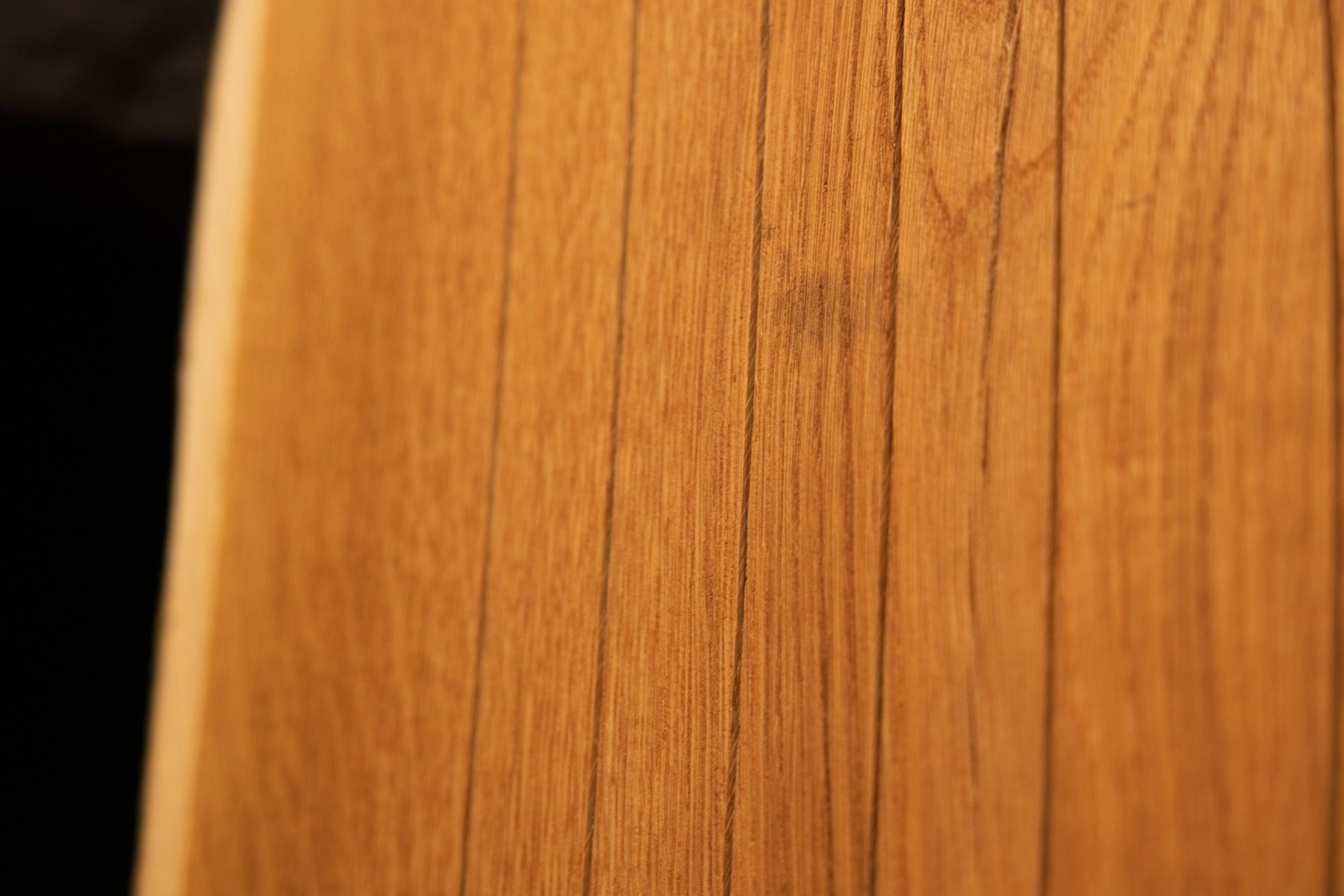 Macro close-up of fine vertical grain lines running along the smooth face of a solid custom architectural oak wood board. 