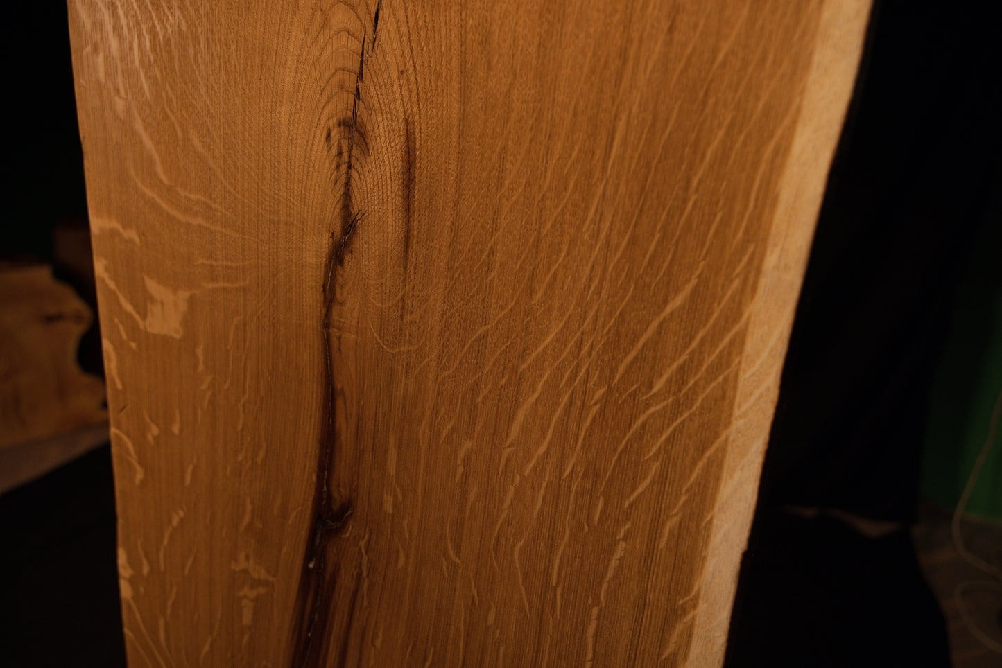 Close-up macro of the upper section on the solid oak architectural panel showing the curved path of a stabilized fissure. 