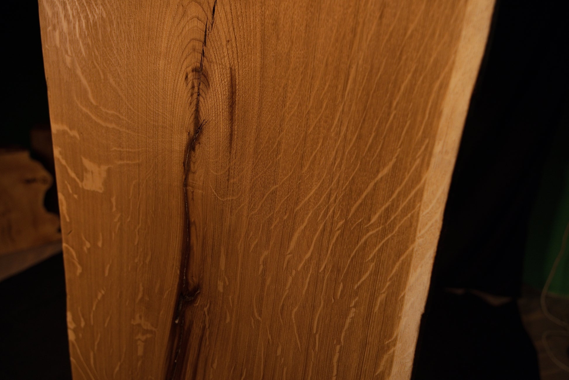 Close-up macro of the upper section on the solid oak architectural panel showing the curved path of a stabilized fissure. 