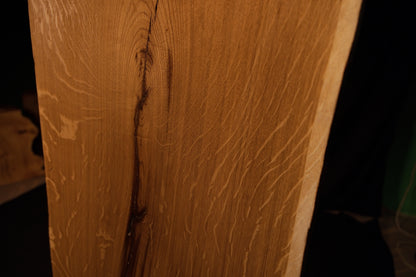 Close-up macro of the upper section on the solid oak architectural panel showing the curved path of a stabilized fissure. 