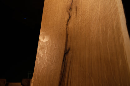 Detailed macro focus on the intersection between fine vertical wood grain and sweeping medullary ray reflections on the slab. 