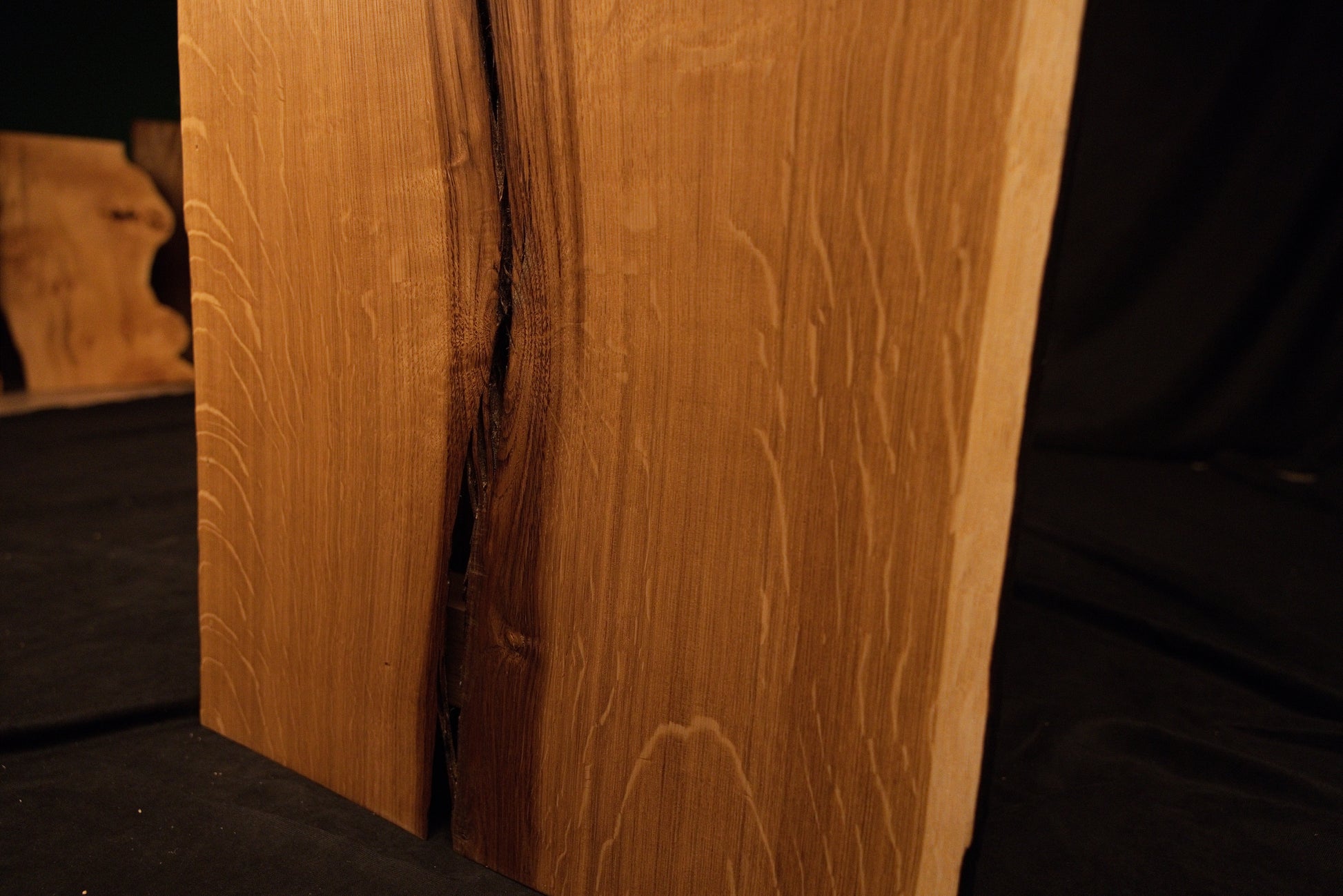 Close-up macro showing a natural wood knot splitting into a delicate fissure across the highly figured solid oak panel face. 