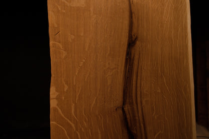 Macro close-up of vertical wood fibers and subtle grain variations along the polished outer edge of the solid oak board. 