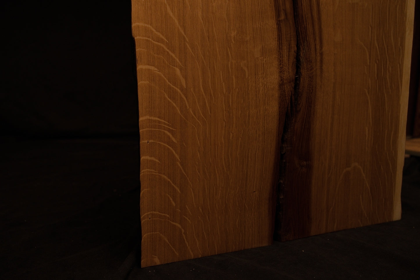 Macro view of an organic wood knot surrounded by expanding rippling grain patterns on the custom solid oak architectural piece. 