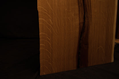 Macro view of an organic wood knot surrounded by expanding rippling grain patterns on the custom solid oak architectural piece. 