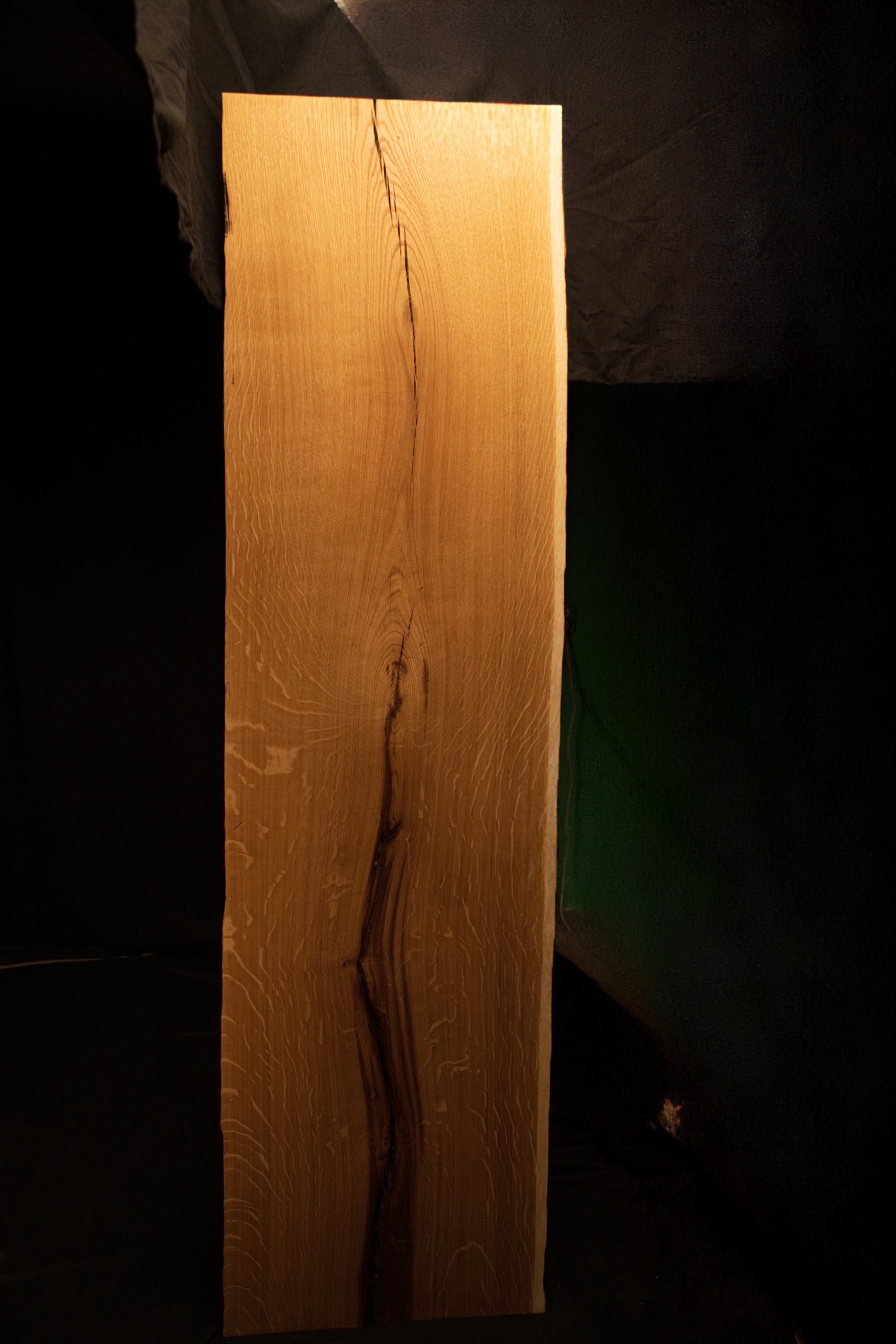 Straight vertical macro perspective of a tight natural fissure running through highly figured grain on the custom oak board. 