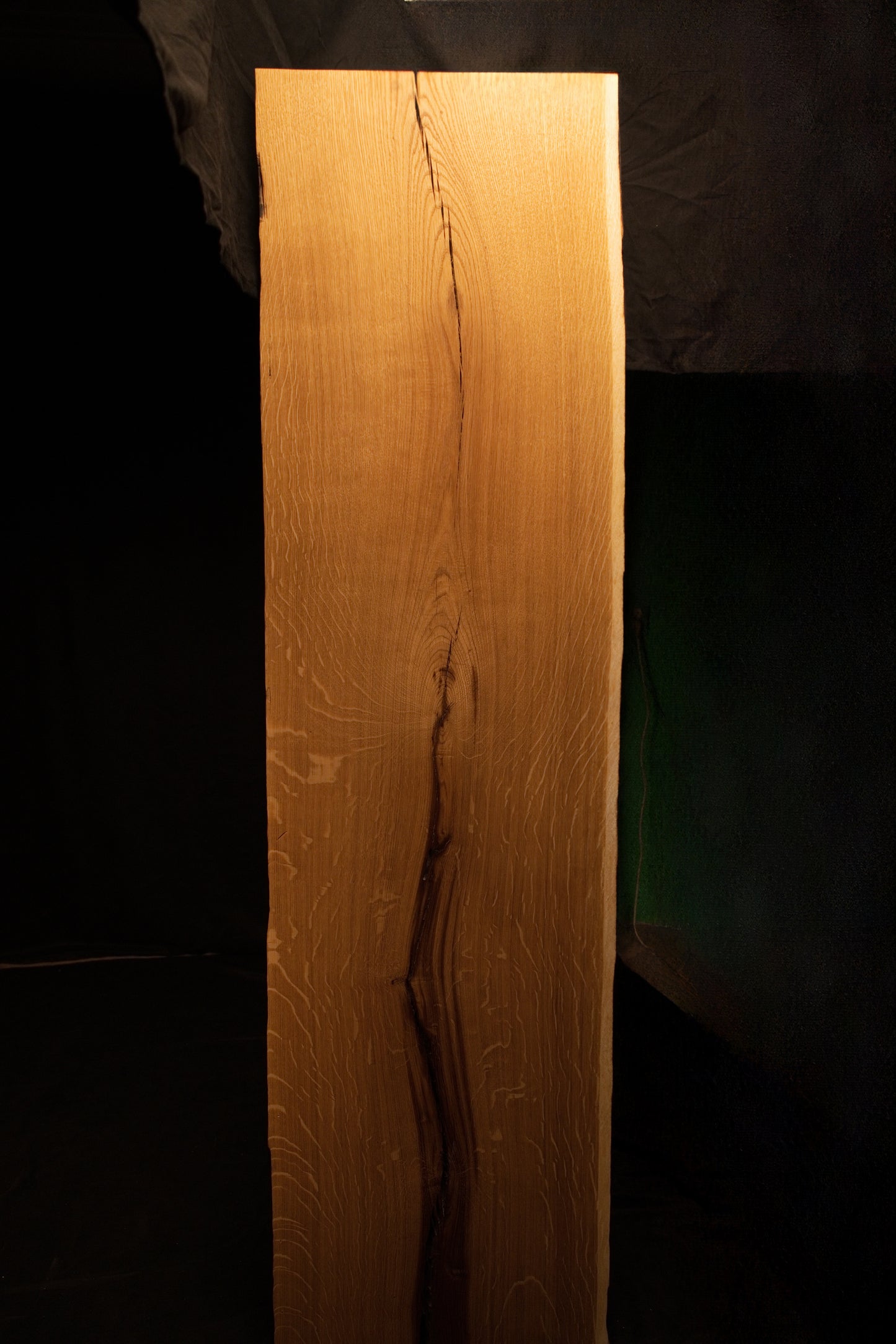 Close-up view of shimmering chatoyant medullary rays shifting across the warm golden surface of the custom architectural oak panel. 