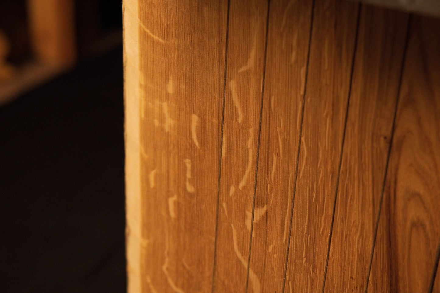 Close-up macro focusing on erratic organic biological markings traversing the vertical grain lines of the custom oak panel. 