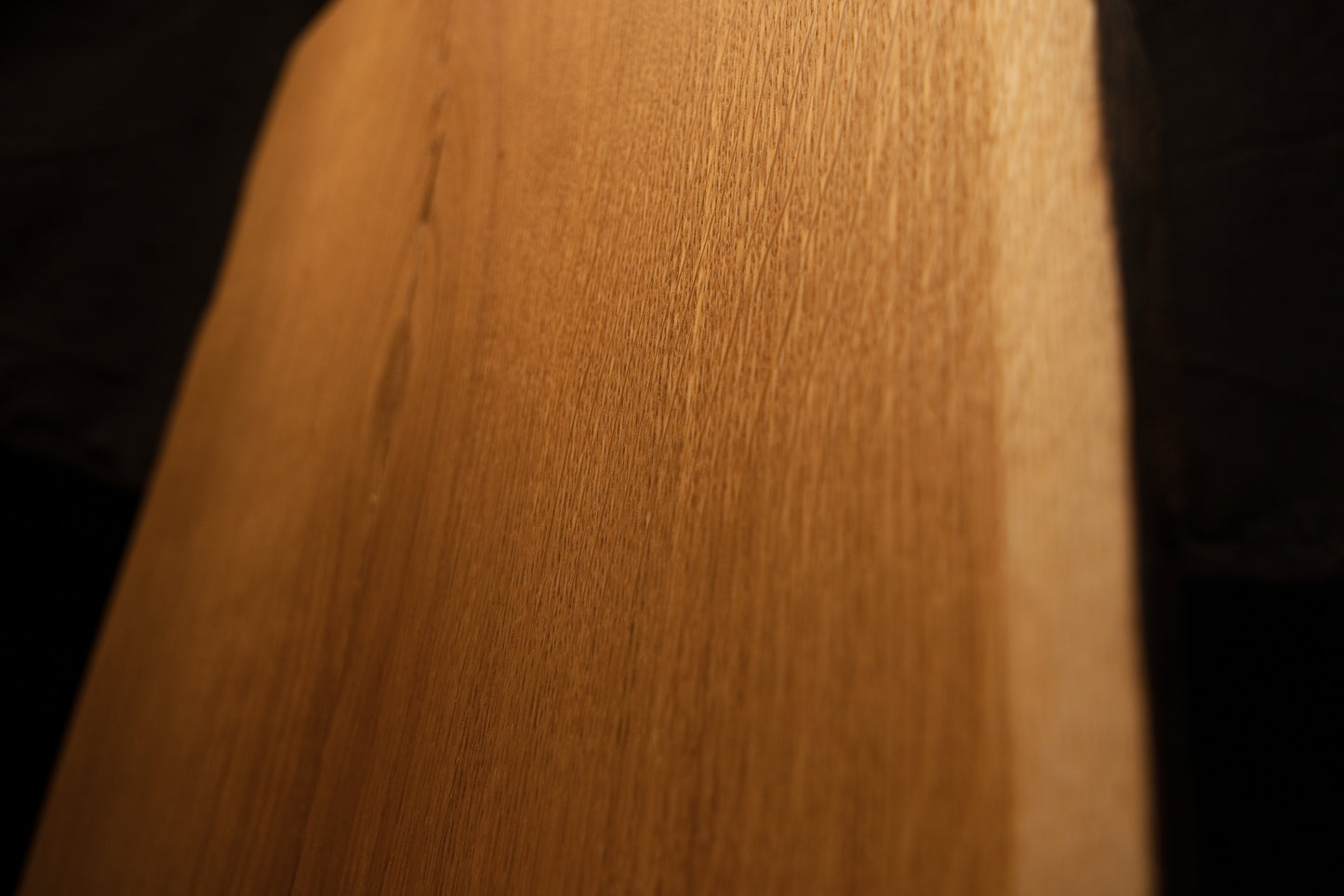 Close-up macro view of smooth vertical grain patterns and rich warm tones along the clean edge of the custom oak slab. 