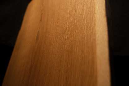 Close-up macro view of smooth vertical grain patterns and rich warm tones along the clean edge of the custom oak slab. 