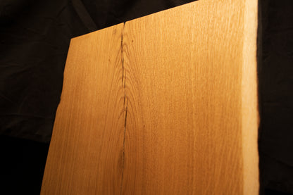 Detailed view focusing on symmetrical cathedral grain loops framing a narrow vertical split at the top of the oak slab. 