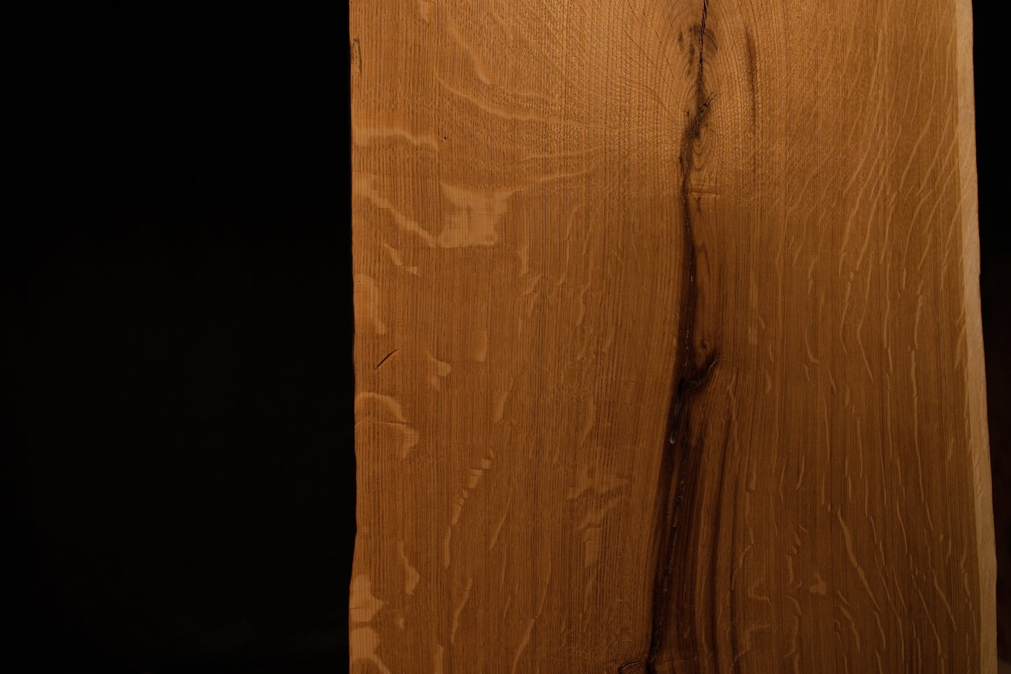 Detailed macro shot highlighting natural medullary ray patterns running alongside a dark fissure on the solid oak panel. 