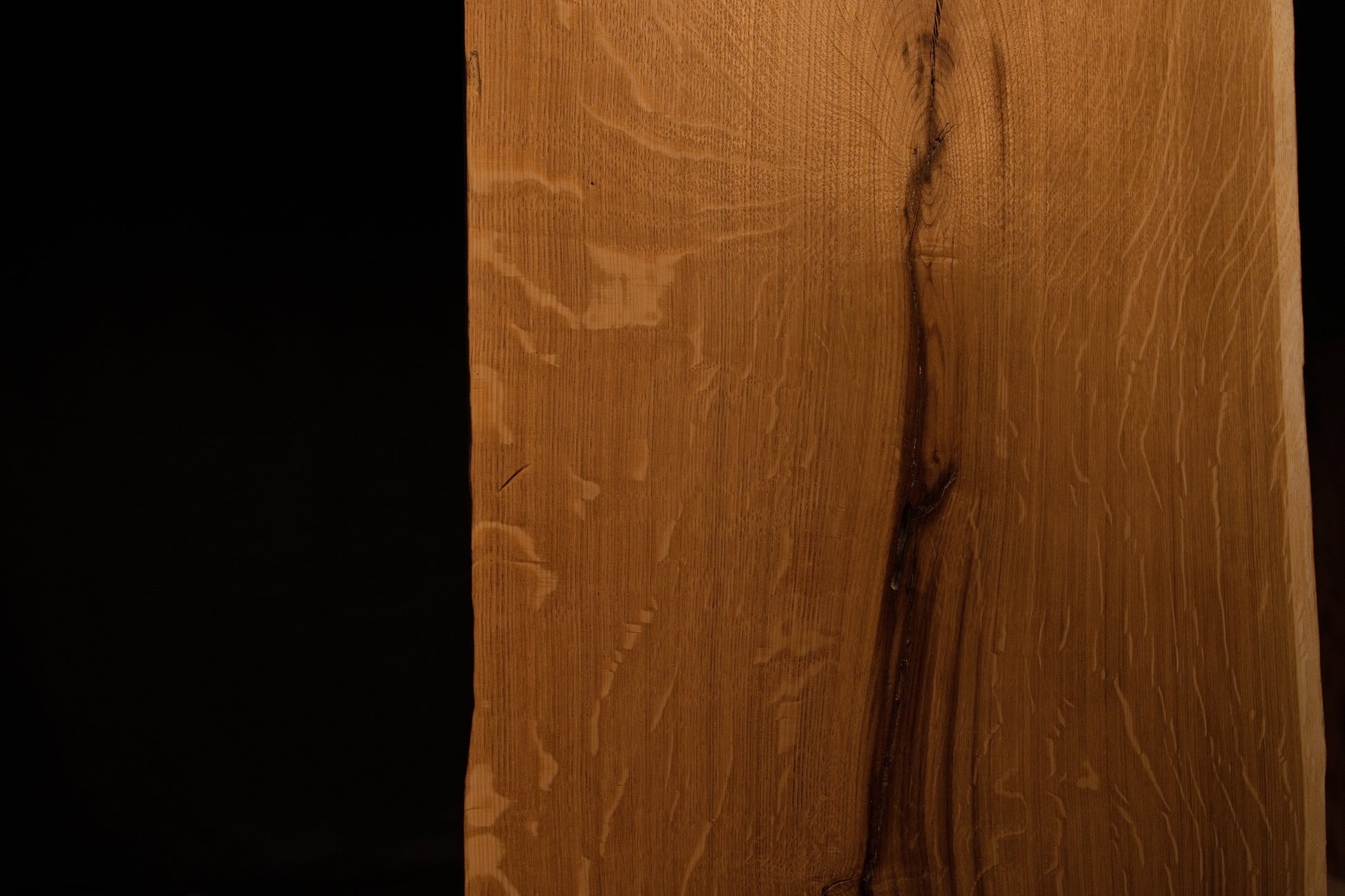Detailed macro shot highlighting natural medullary ray patterns running alongside a dark fissure on the solid oak panel. 