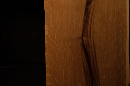 Close-up macro capturing rich amber wood tones and complex grain convergence around a central split in the oak board. 