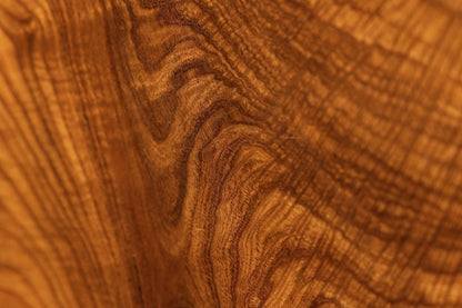 Dense undulating golden-brown wood fibers flow seamlessly across the polished surface of the custom-carved root sculpture.  