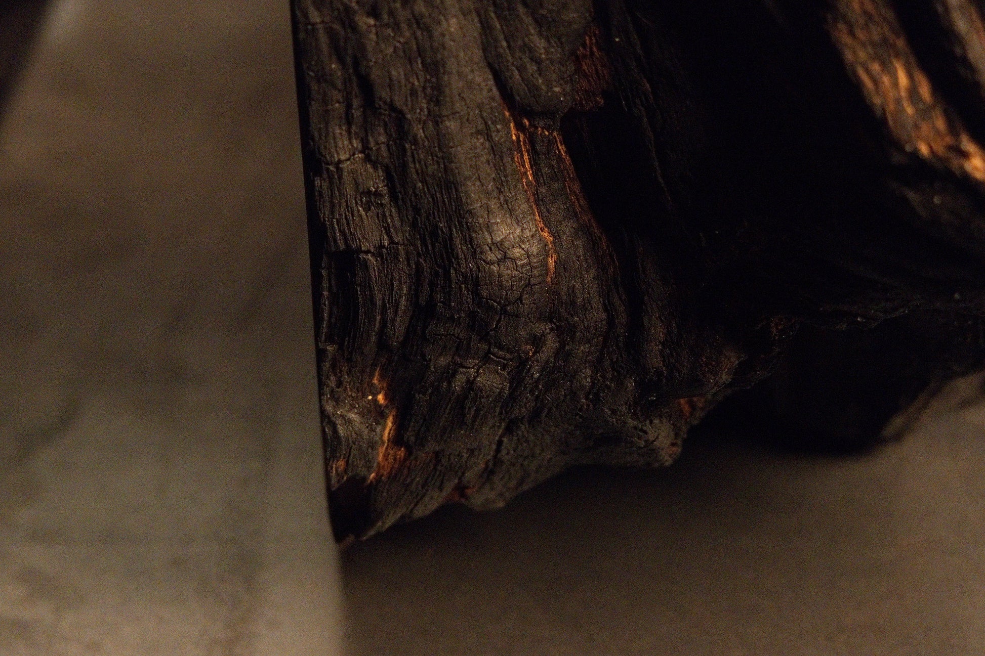 Dark carbonized timber texturing tapers smoothly downward toward a sleek metallic installation foundation platform.  