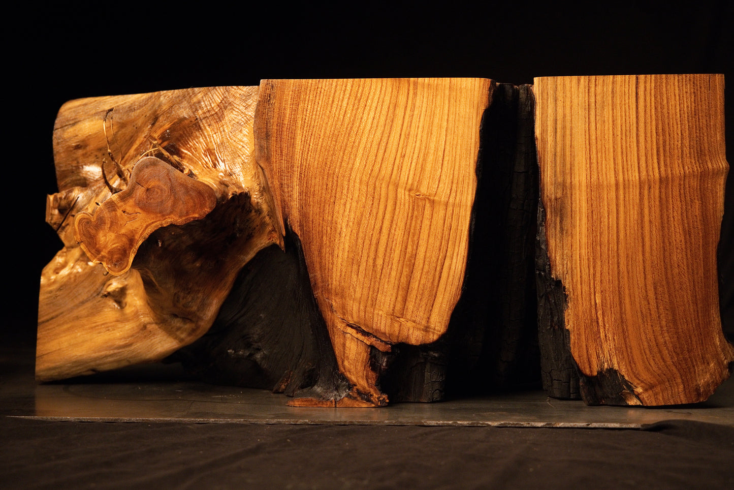 Dual-block architectural wooden bench featuring warm golden vertical grain patterns and dark charred interior void faces.  
