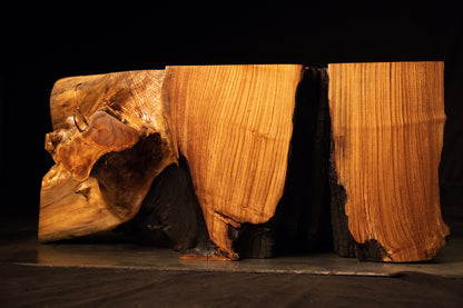 Perspective view of the split wooden bench showcasing contrasting golden surface faces and deep carbonized cores.  