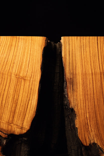Looking down into the upper gap between split timber blocks to reveal dark, heavily charred interior cavity walls.  