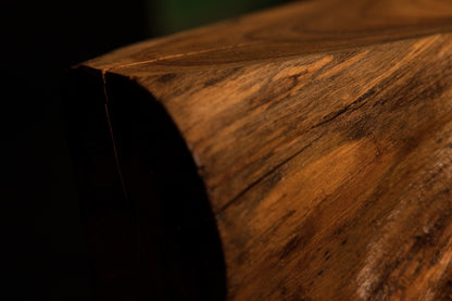 Rounded timber corner highlighting fine radial surface checking and warm golden-brown annular growth ring patterns.  
